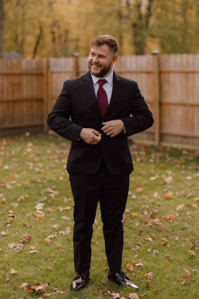 Groom getting ready – Tom adjusting his jacket with his family nearby before the wedding ceremony.
