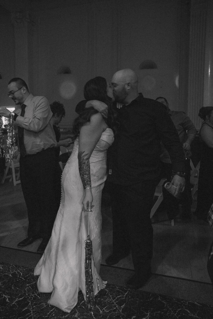 Black and white photo of the couple sharing a kiss on the dance floor during their New Year’s Eve wedding reception at the Hanny Manny Building in Olean, NY.